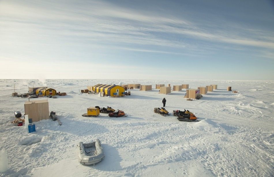 A man walks towards snow machines past the plywood hutches and tents that make up the Applied Physics Lab Ice Station in the Arctic north of Prudhoe Bay, Alaska