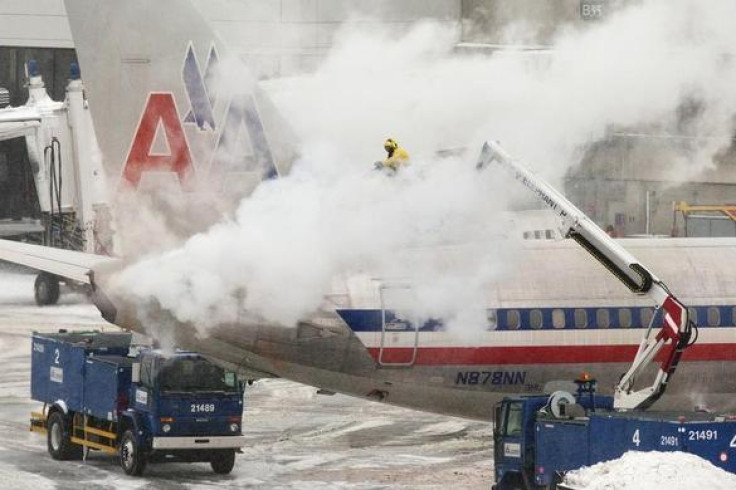 An American Airlines crew member sprays de-icing solution on a plane during a winter nor'easter snow storm in Boston, January 2, 2014. REUTERS-Dominick Reuter