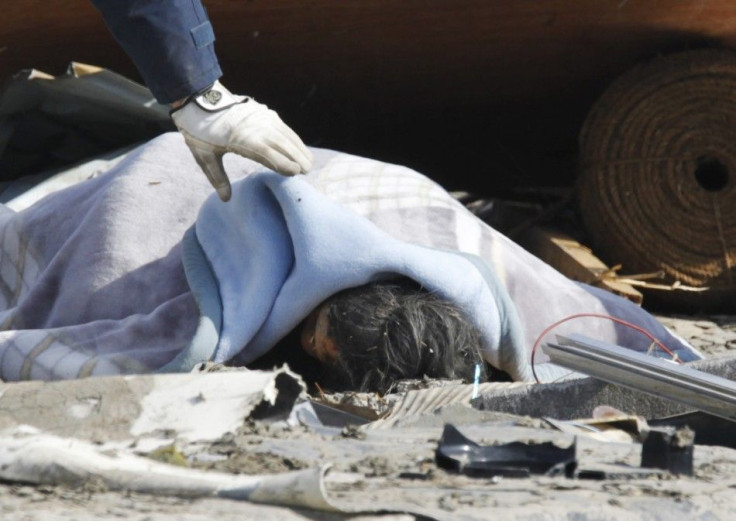 A police officer checks a dead body at a village destroyed by an earthquake and tsunami in Ofunato, northeast Japan