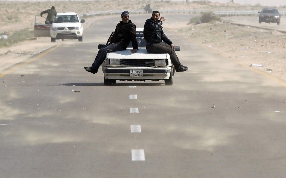 Rebel fighters ride on a car along the Benghazi-Ajdabiyah road near Ajdabiyah 