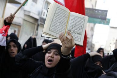 A Bahraini woman holds a Koran over her head as she shouts anti-government slogans during a protest in the mainly Shi'ite village of Diraz