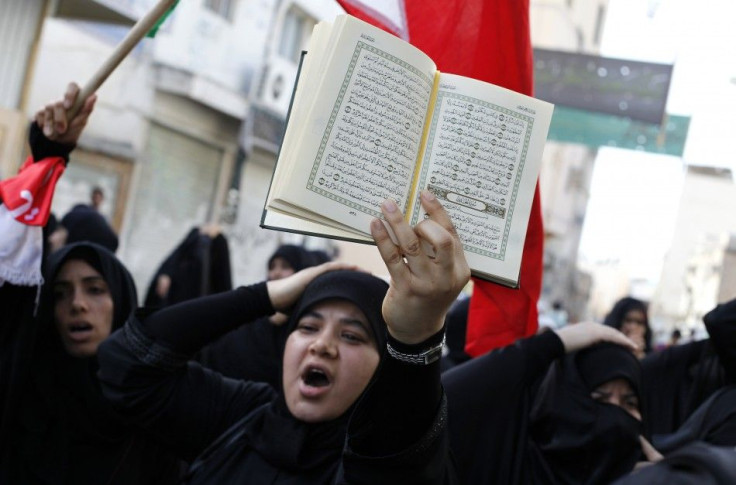 A Bahraini woman holds a Koran over her head as she shouts anti-government slogans during a protest in the mainly Shi'ite village of Diraz
