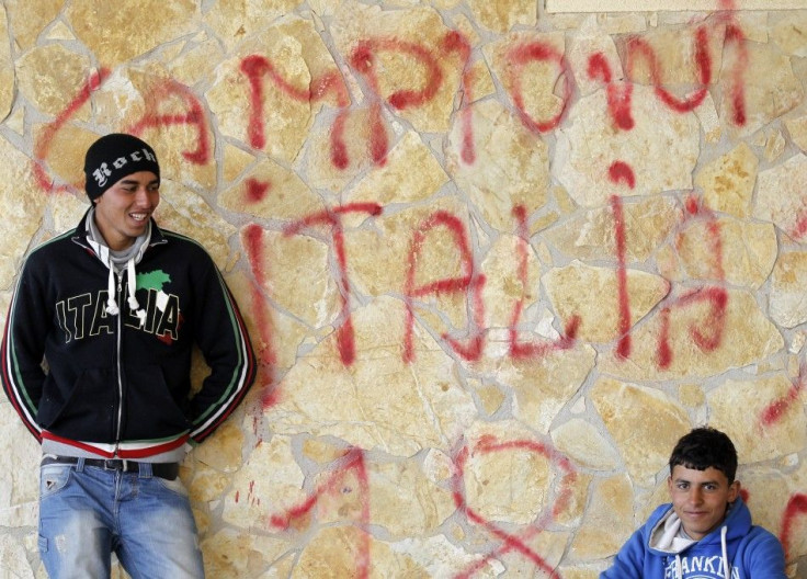 Two men fleeing the unrest in Tunisia rest after arriving at the southern Italian island of Lampedusa