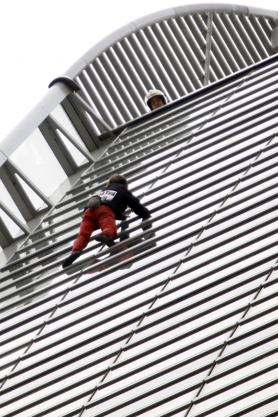 French climber Alain Robert scales the 185 metre GDF Suez Tower at the La Defense business district