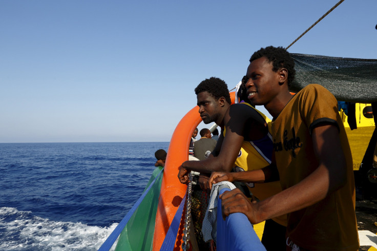 Migrants look out across the Mediterranean after being rescued by a European ship