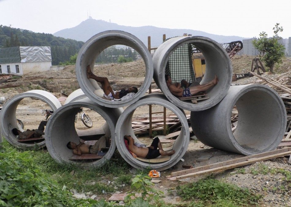 Migrant workers nap inside cement pipes at a construction site in Xiangfan