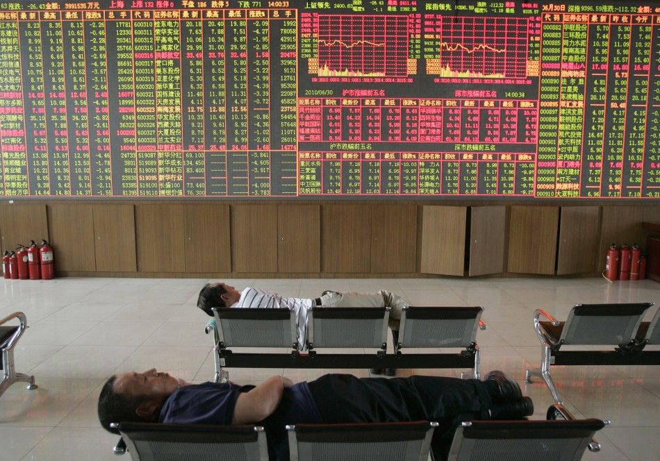 Investors sleep in front of an electronic board showing stock information at a brokerage house in Taiyuan