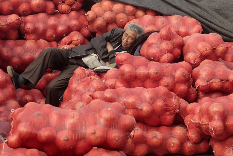 A vendor naps on bags of pumpkins at a market in Tianjin municipality
