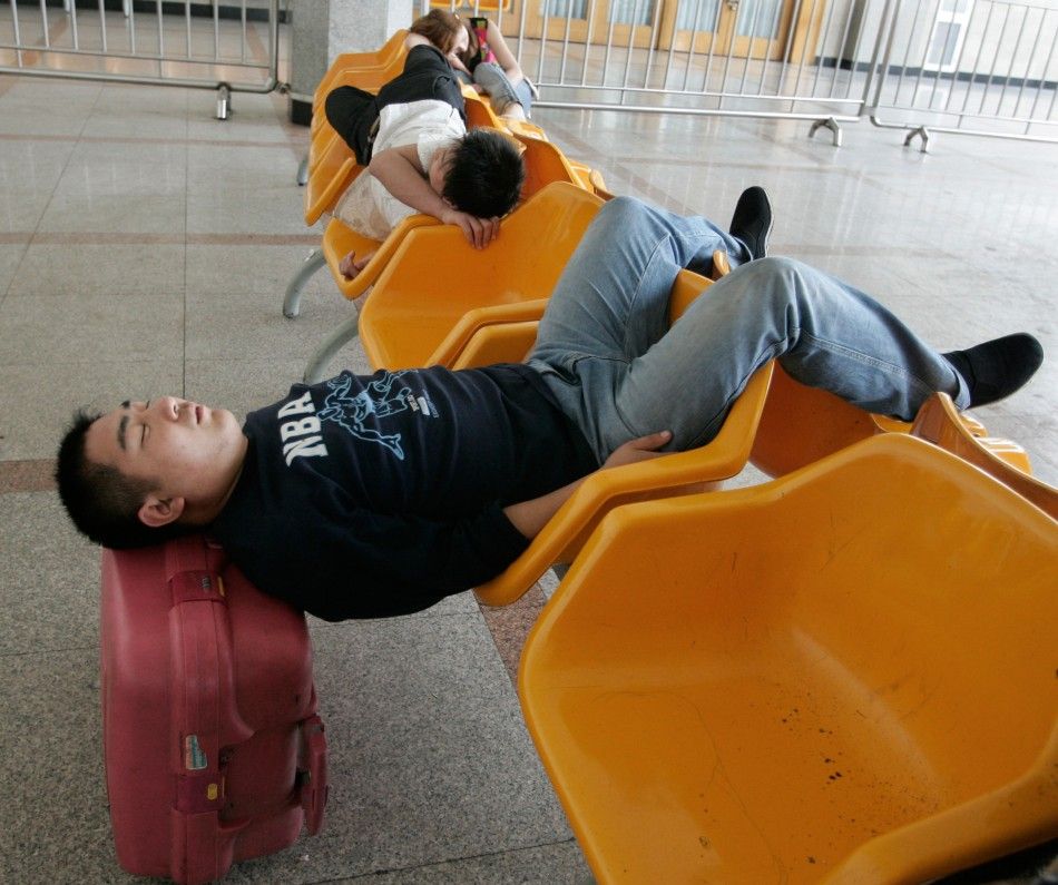 A traveller sleeps while waiting for his train at the Beijing Railway Station