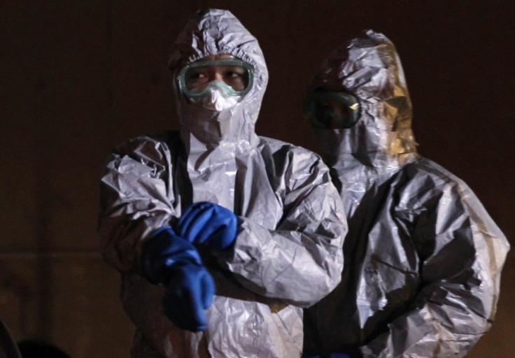 Officials in protective gear stand next to people who are from the evacuation area near the Fukushima nuclear plant.