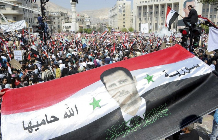 Syrians display a giant national flag with a picture of Syria's President Assad during a pro-government rally at the central bank square in Damascus
