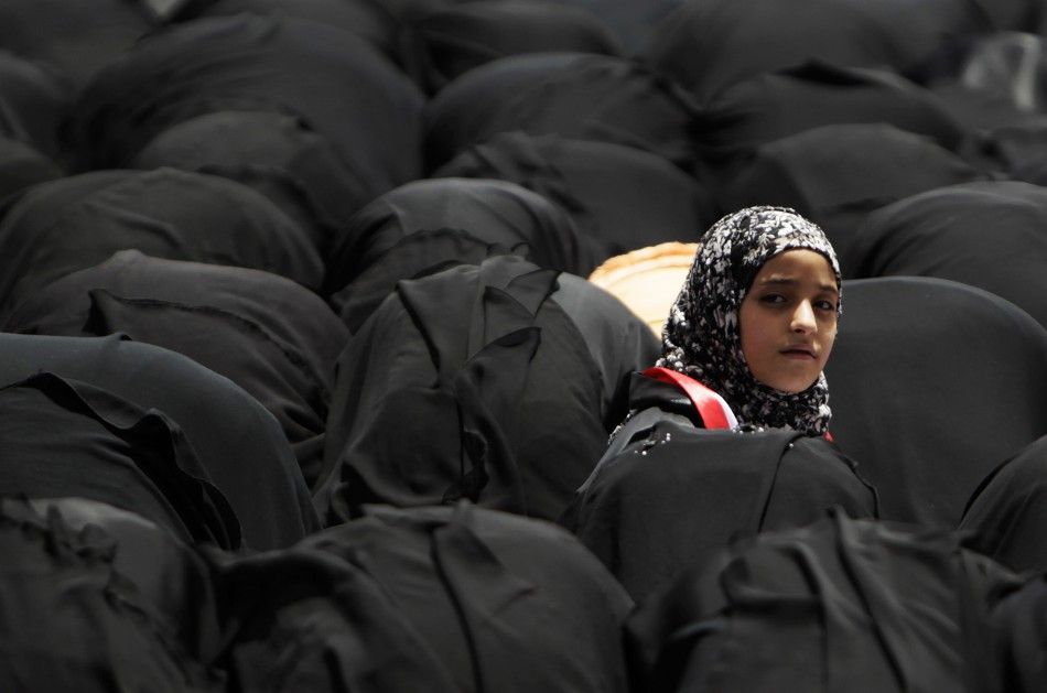 A girl looks up among women praying during an anti-government rally in Sanaa University
