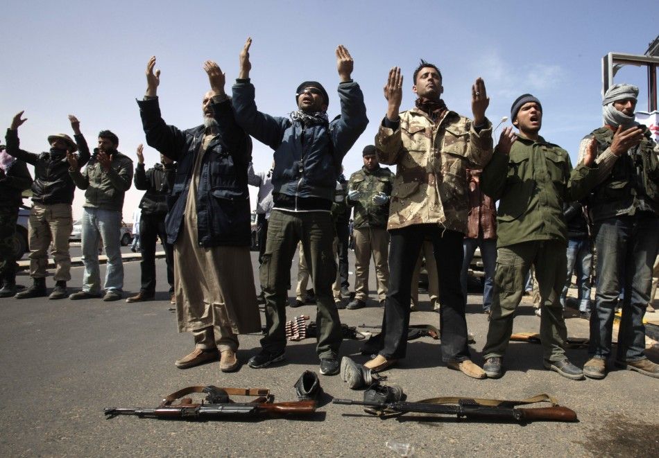 Anti-Gaddafi rebels pray at a checkpoint at Ras Lanuf