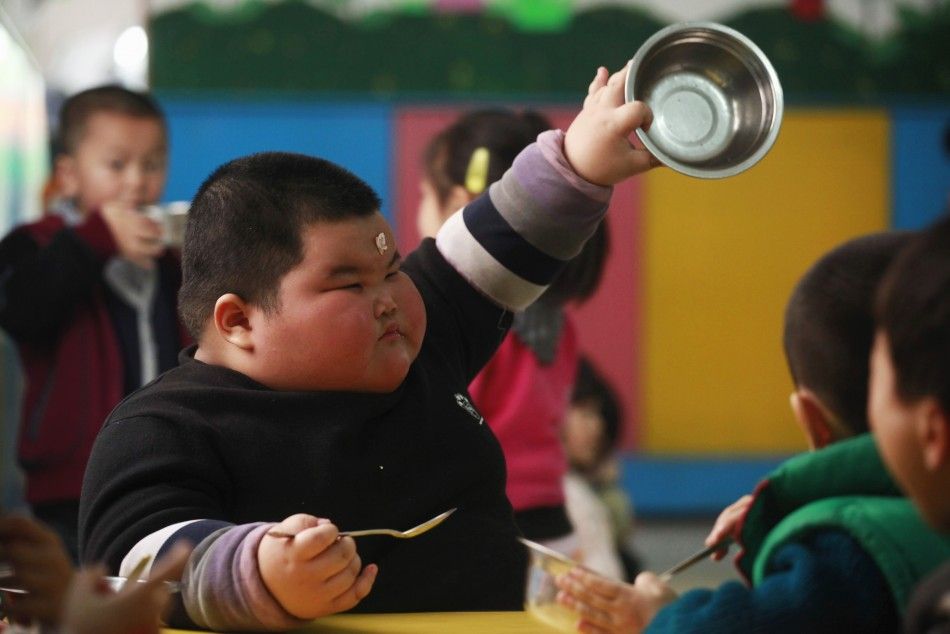 Lu Zhihao shows his empty rice bowl to his teacher during lunch time at a kindergarten in Foshan