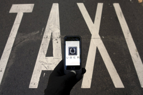 File photo of the logo of car-sharing service app Uber on a smartphone over a reserved lane for taxis in a street in Madrid