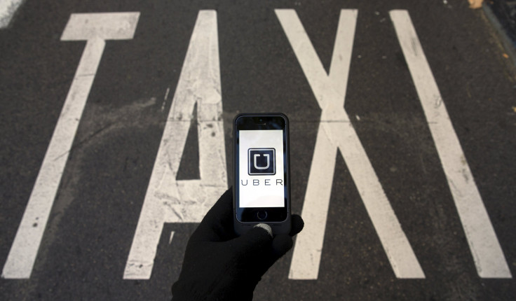 File photo of the logo of car-sharing service app Uber on a smartphone over a reserved lane for taxis in a street in Madrid