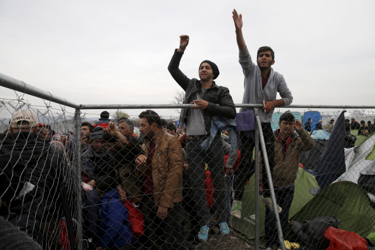 Refugees standing on a fence near to the Greek-Macedonian border.