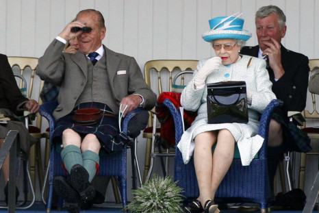 Queen applies lipstick as she sits next to her husband Prince Phillip