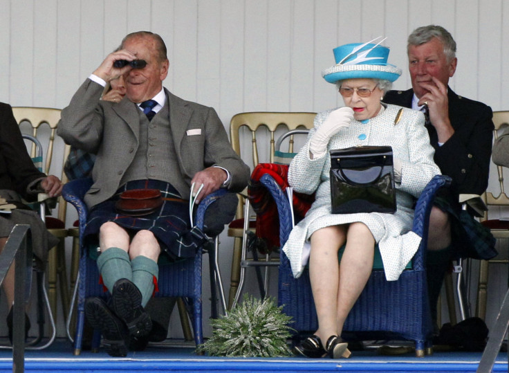 Queen applies lipstick as she sits next to her husband Prince Phillip