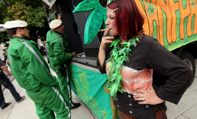 BERLIN - AUGUST 07: A young woman smokes a legal herb called damian as policemen stand nearby prior to marching in support of the legalization of marijuana in Germany during the annual Hemp Parade