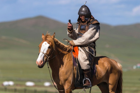Mongolian rider on a horse uses mobile phone