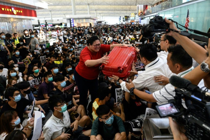 A tourist struggles to get past protesters and reach a security gate at the Hong Kong airport departure hall