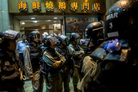 Hong Kong riot police stand in front of a restaurant while patrolling after an anti-government rally which, for the first time in weeks, saw no major confronations with officers