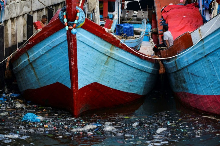 Fishing boats sit in trash-filled waters in Banda Aceh, Indonesia on July 16, 2019