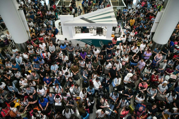 Travellers wait in the terminal of Hong Kong's international airport after a train service linking it to the city was cancelled due to pro-democracy protesters