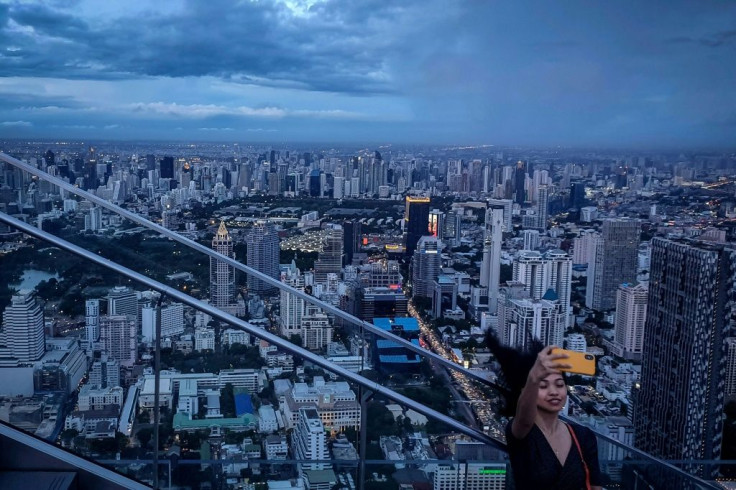 This picture taken on June 26, 2019 shows a tourist taking a selfie photograph in front of the city skyline from the Mahanakorn Skywalk's observation deck area, located 314 metres above the ground, in Bangkok