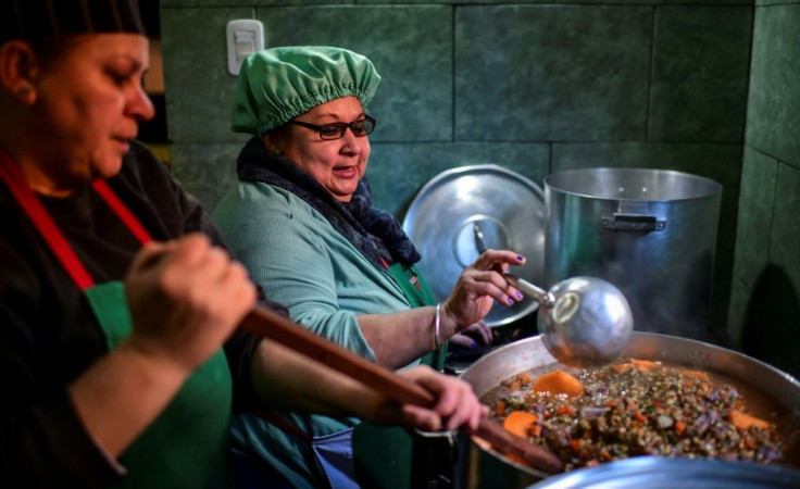 Women serve food at a soup kitchen which feeds at least 200 people hit hard by the economic crisis