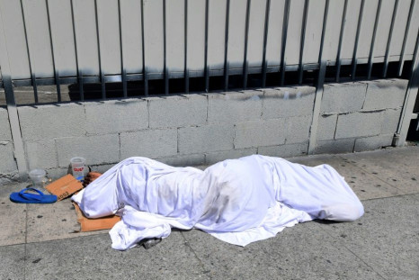 A homeless person' sleeping under a sheet on a sidewalk in Los Angeles, California on August 22, 2019, home to one of the nation's largest homeless populations