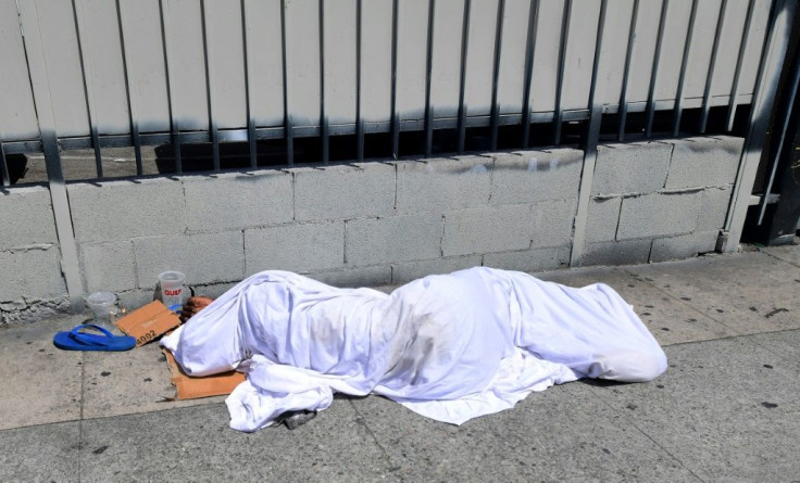 A homeless person' sleeping under a sheet on a sidewalk in Los Angeles, California on August 22, 2019, home to one of the nation's largest homeless populations