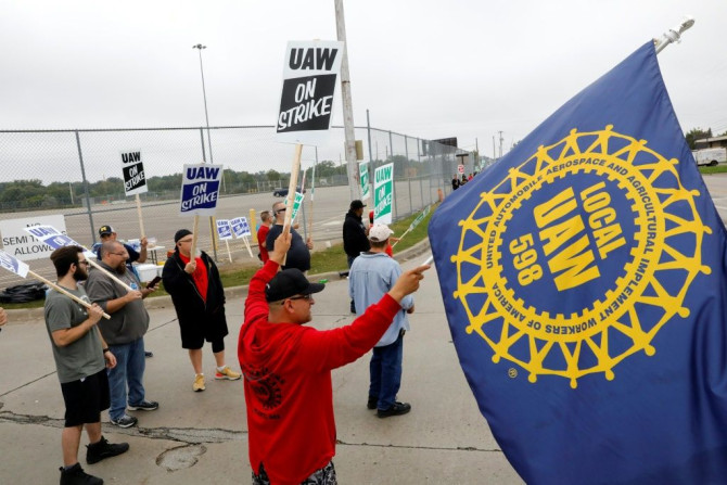 Striking members of the United Auto Workers (UAW) wave flags and banners at the General Motors plant in Flint, Michigan
