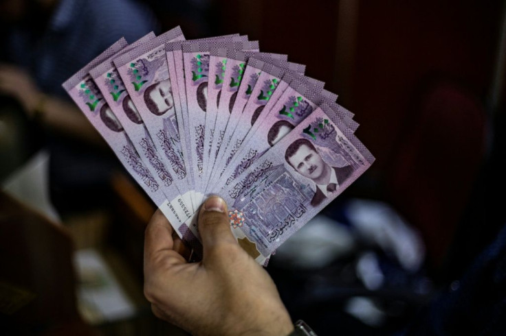 A merchant holds a wad of Syrian pounds, bearing a portrait of Syrian President Bashar al-Assad, at a market in the Kurdish-majority city of Qamishli in northeast Syria