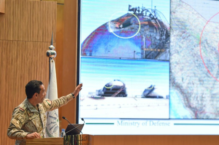 Saudi defence ministry spokesman Turki bin Saleh al-Malki shows off pictures as he alleges that strikes on the country's oil infrastructure came from the north and were 'unquestionably' sponsored by Iran