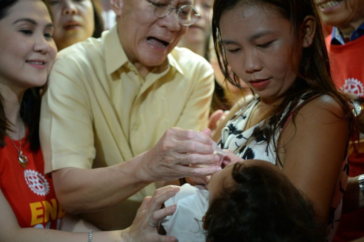 Philippine Health Secretary Francisco Duque (C) administers a dose of oral polio vaccine at the start of a programme to immunise millions of children following the country's first outbreak in nearly two decades