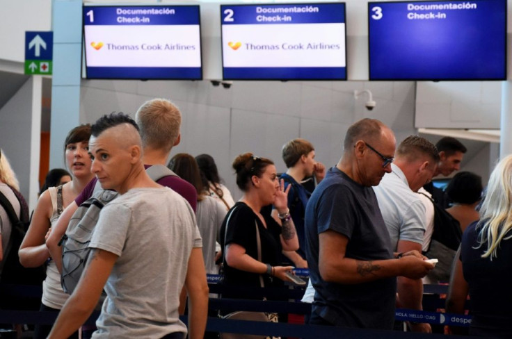 Passengers stand in line at the closed Thomas Cook check-in desk at the airport in Cancun, Mexico, on September 23, 2019