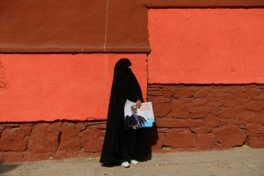 An Afghan woman holds election posters for Abdullah Abdullah -- the current chief executive officer and one of the front-runners