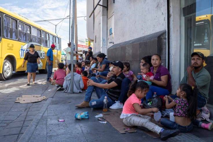 Migrants, mostly from Mexico, are pictured sitting on the ground waiting near the Paso del Norte Bridge at the Mexico-US border, in Ciudad Juarez, Mexico, on September 12, 2019.