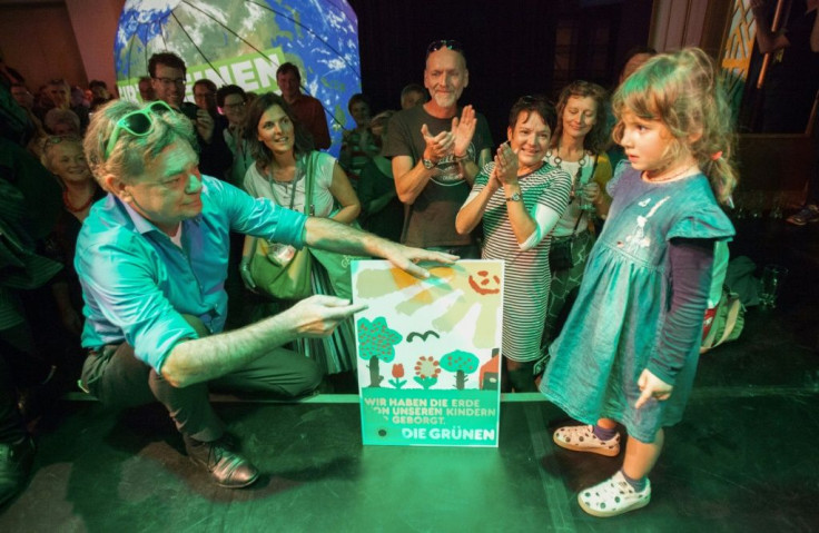 Austrian Green party head Werner Kogler holds a placard reading 'We only borrowed the earth from our children' after the exit poll results came in on Sunday