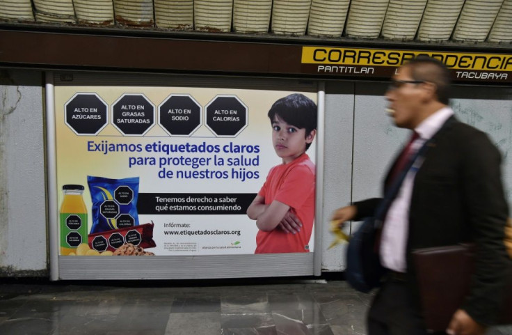 "We demand clear labeling to protect the health of our children," reads the sign in the Mexico City subway, which shows sample junk food warnings of black hexagons with white lettering