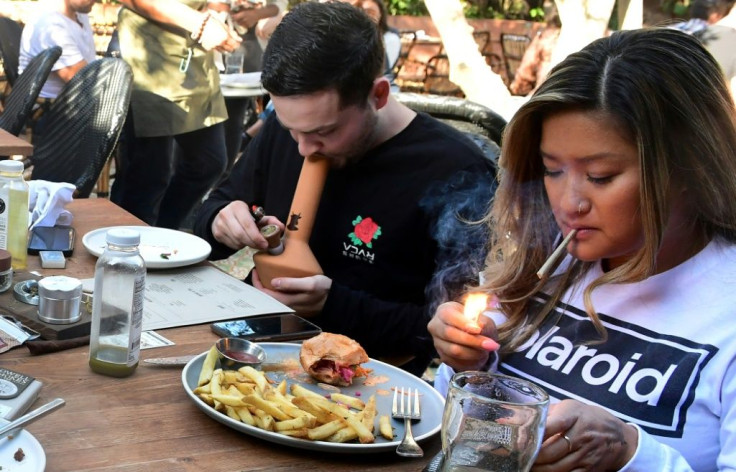 Will Halverson (L) smokes from a bong as Mimi Bui lights a joint with their meal at Lowell Farms: A Cannabis Cafe in West Hollywood, California
