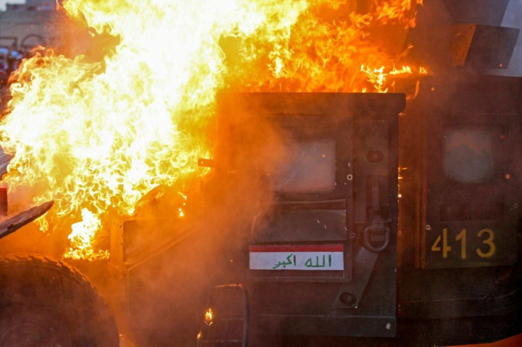 A riot police vehicle burns during clashes between protesters and the police in Baghdad