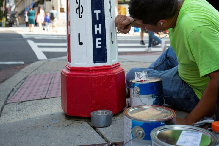 Painter Gerson Gomez, working with artist Charles Bergen (not pictured), refurbishes an old Washington call box, which formerly alerted firefighters, to honor Julia Ward Howe who wrote "The Battle Hymn of the Republic"