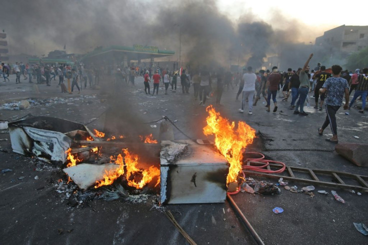Iraqi protesters burn objects to block the road during clashes amidst demonstrations against state corruption, failing public services, and unemployment in the Iraqi capital