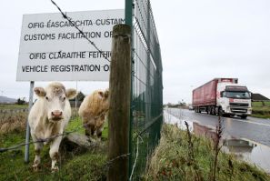 (FILES) In this file photo taken November 14, 2018, cows stands under a sign at a disused Irish border vehicle registration and customs office outside Dundalk, Ireland, near the border crossing with Northern Ireland; the issue of how to respect EU rules w