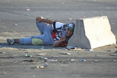 An Iraqi protester takes cover during a protest in central Baghdad on October 4, 2019