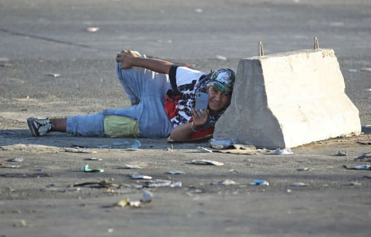 An Iraqi protester takes cover during a protest in central Baghdad on October 4, 2019
