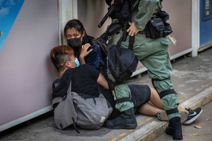 Police chase down a couple wearing face masks in Hong Kong's Central business district after the city's leader outlawed face coverings at protests